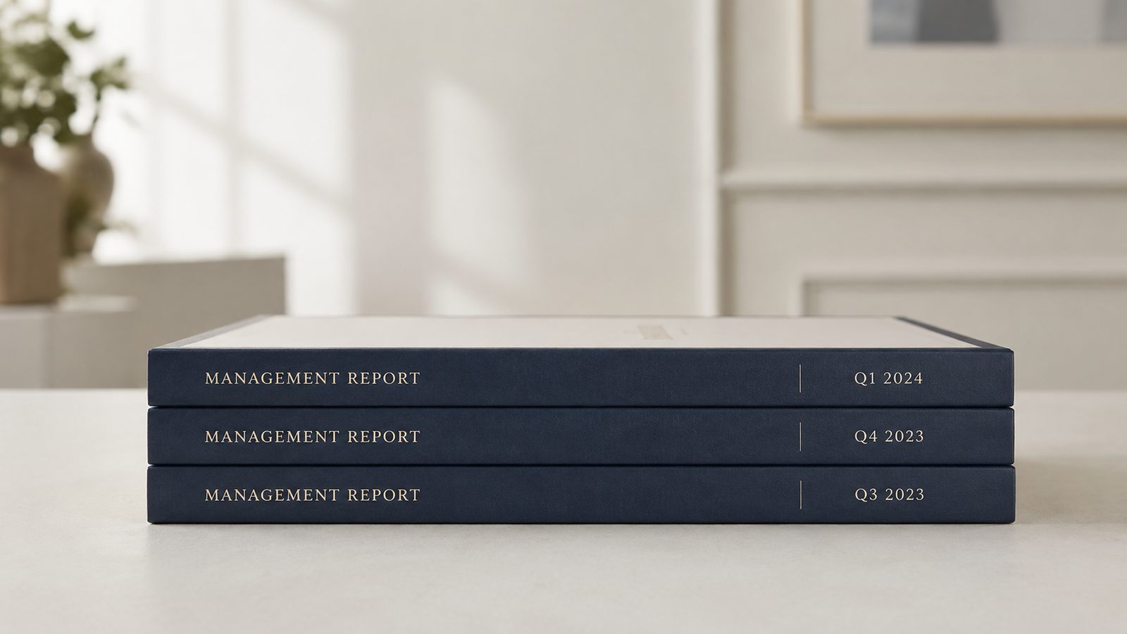 Three bound quarterly management reports stacked on a pale desk